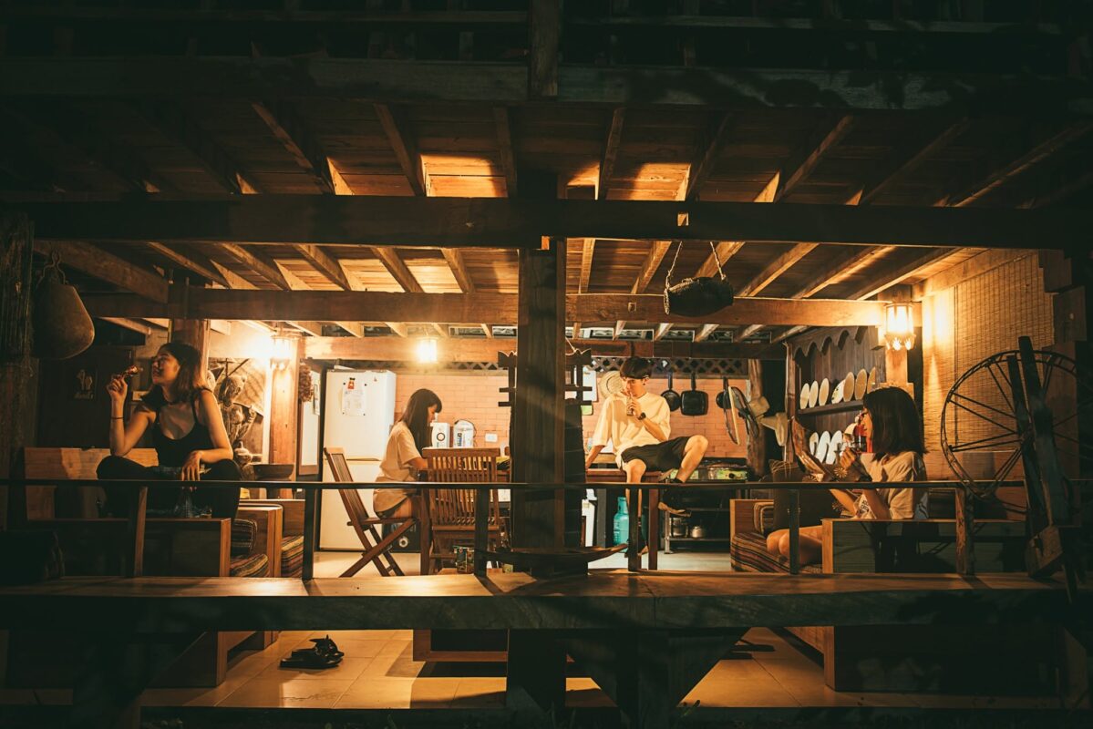 Guests relaxing together in a wooden living area at Rice Barn and Rooms in Chiang Mai